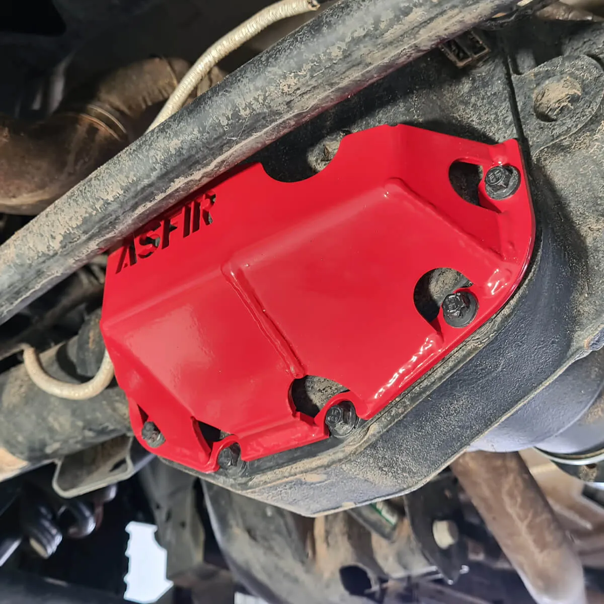 Red ASFIR differential skid plate installed on a Nissan axle